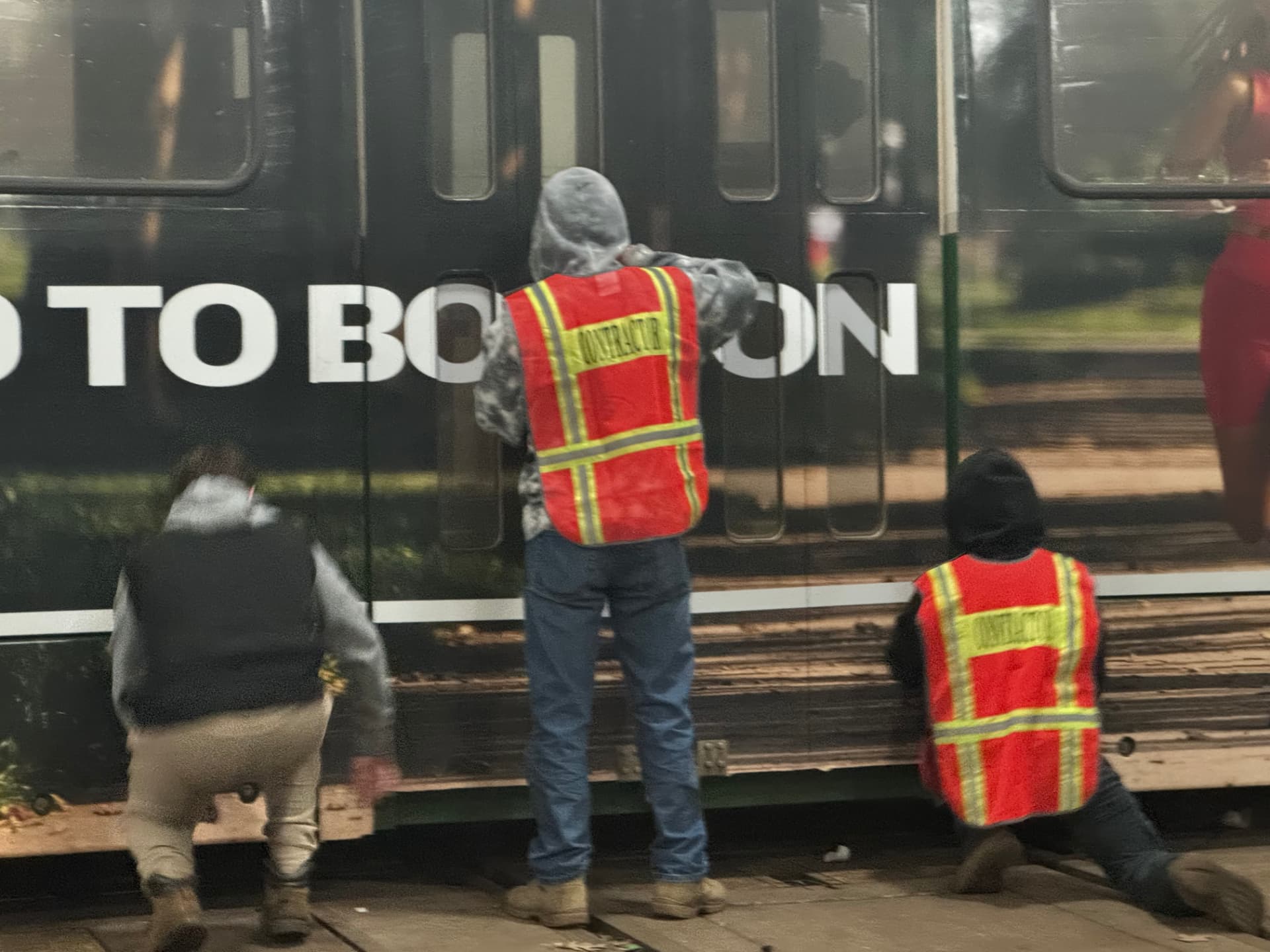 Install crew applying large format vinyl to a transit rail car at night