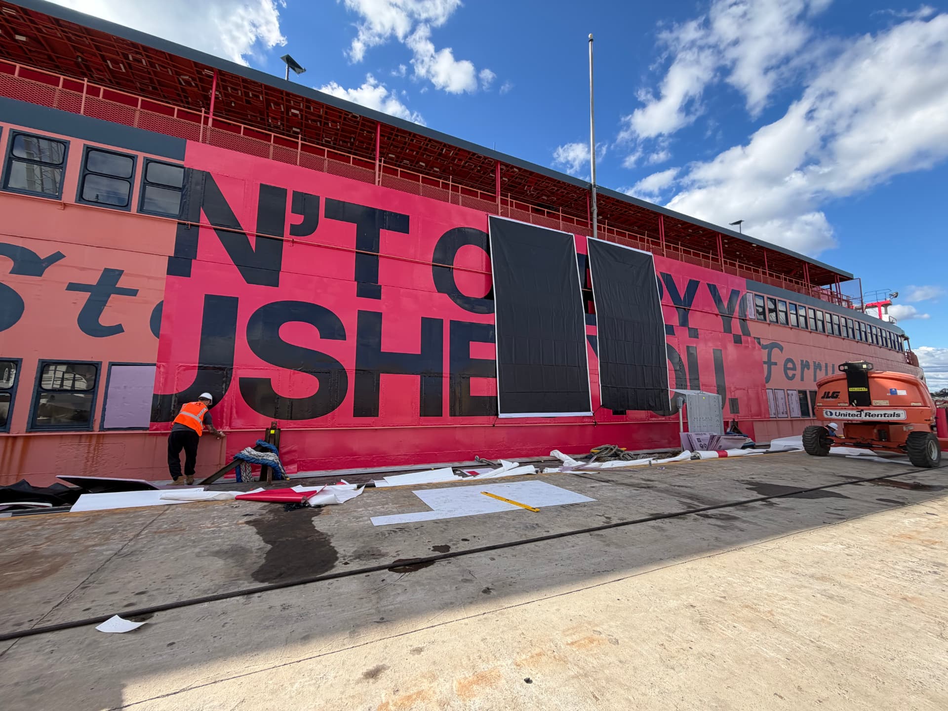 Crew installing a large format pink typographic wrap on a passenger ferry hull