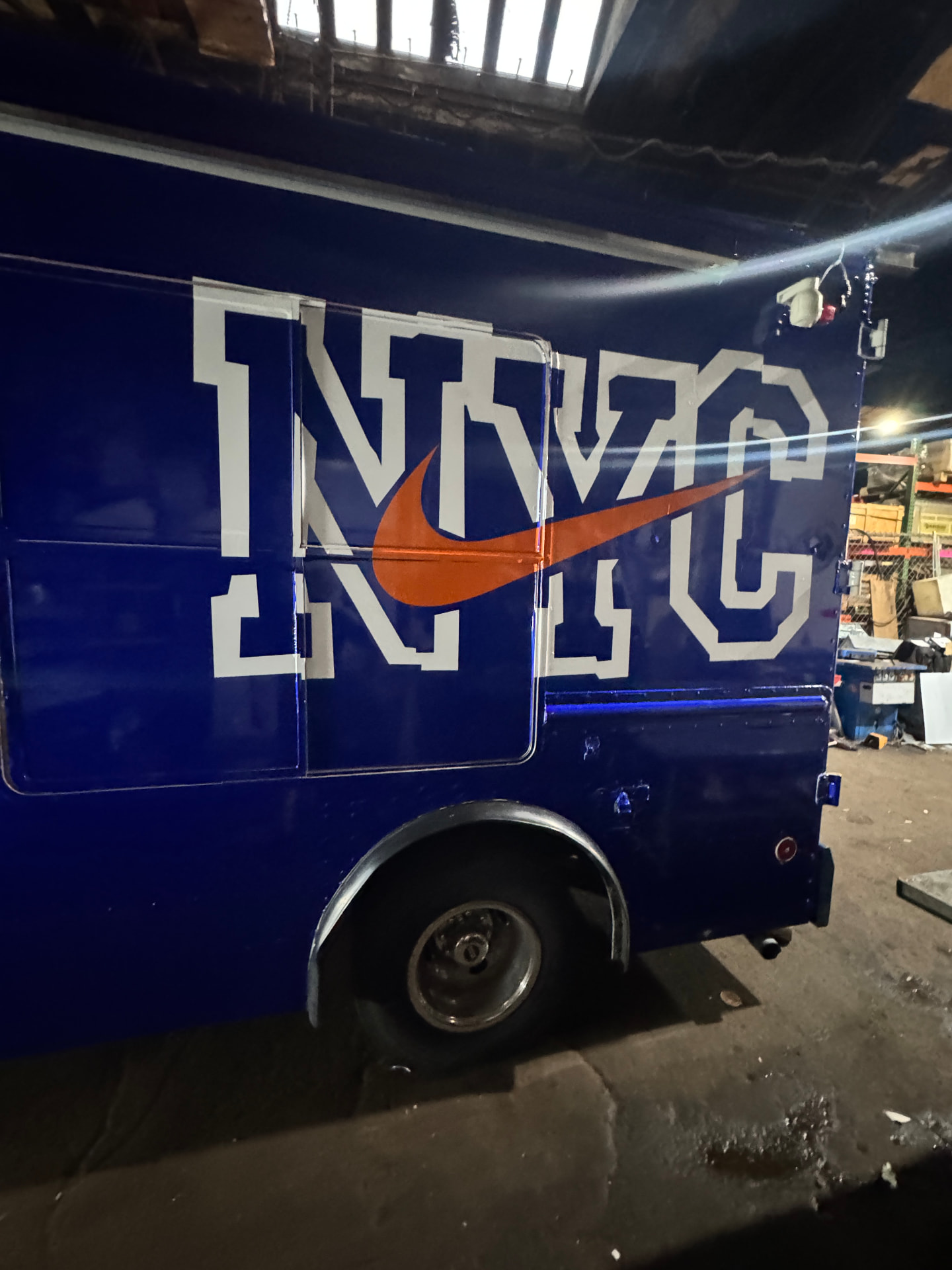 Blue NYC step van with large white lettering and orange swoosh graphics