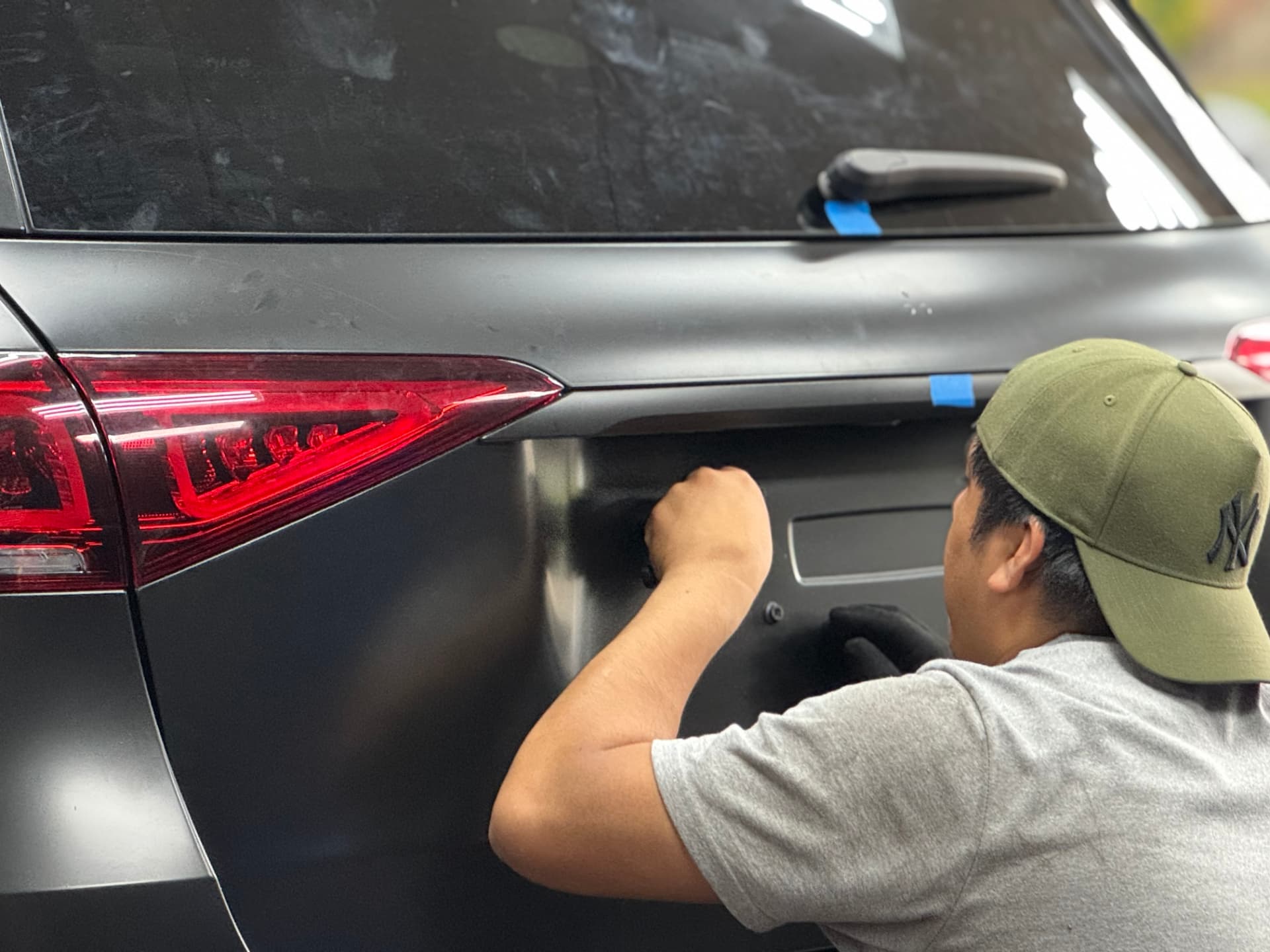 Technician wrapping the rear hatch of an SUV in satin black film