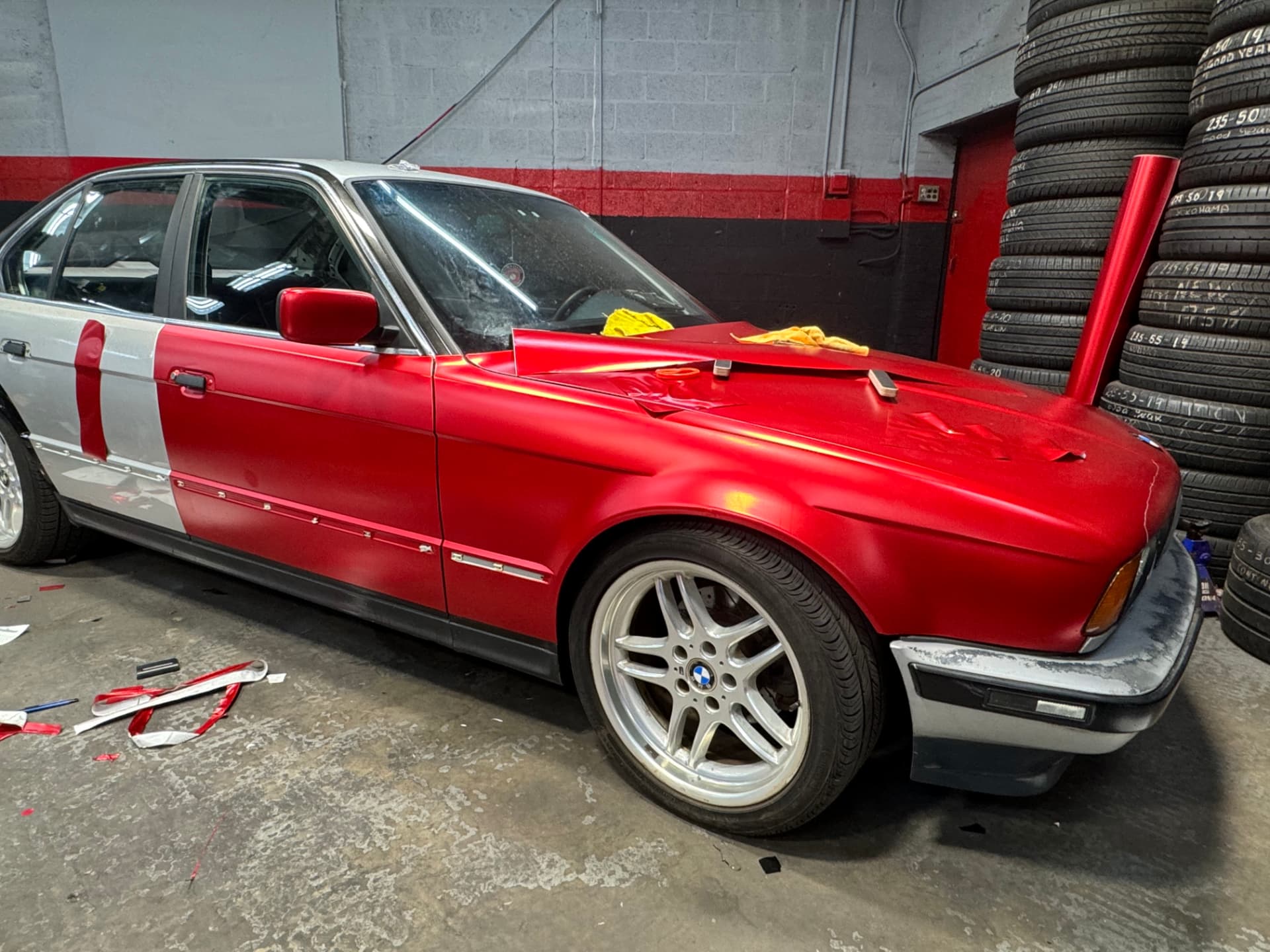 Satin red vinyl being installed panel by panel on a BMW sedan