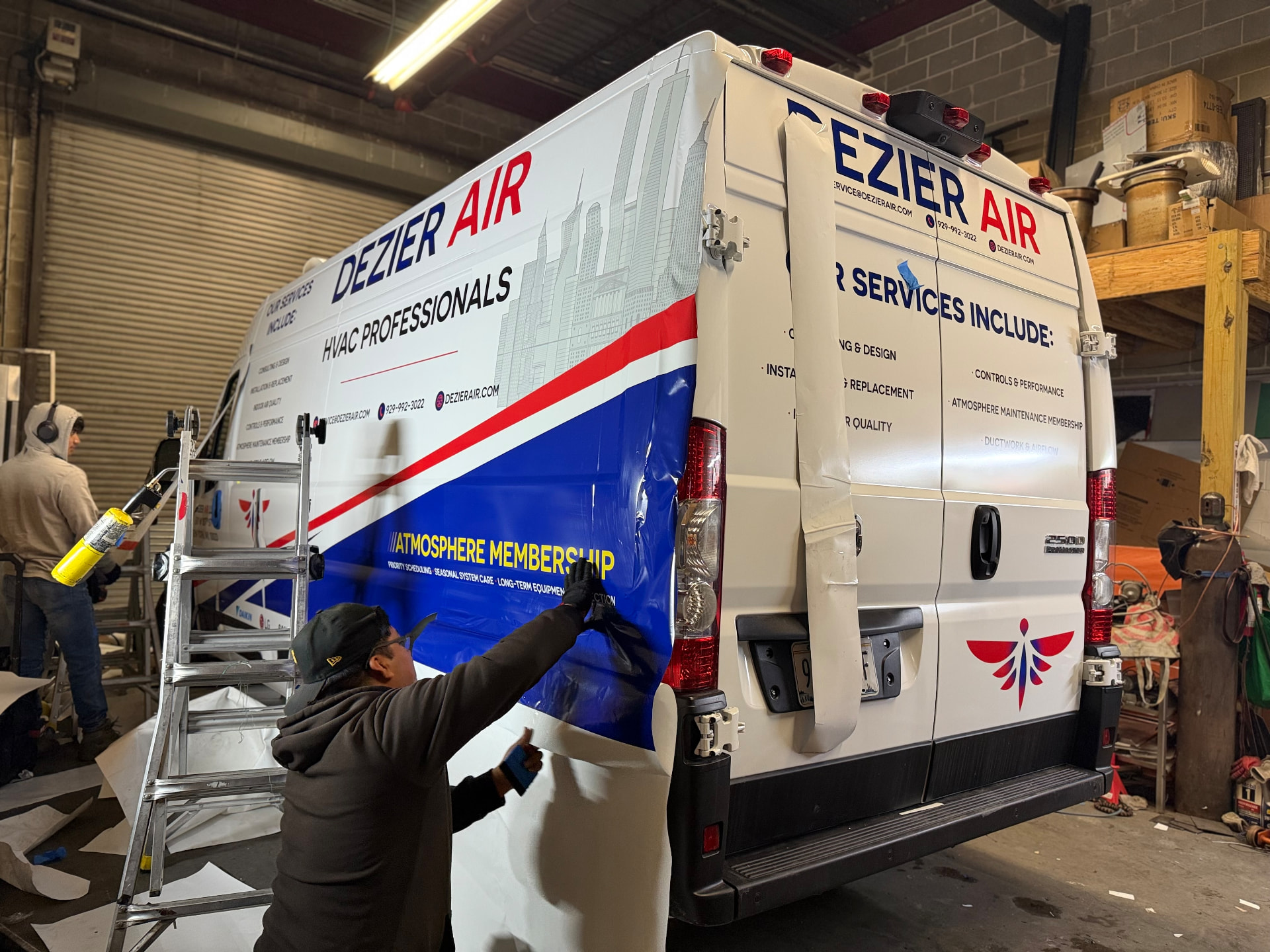 Crew installing a Dezier Air HVAC fleet wrap on a cargo van