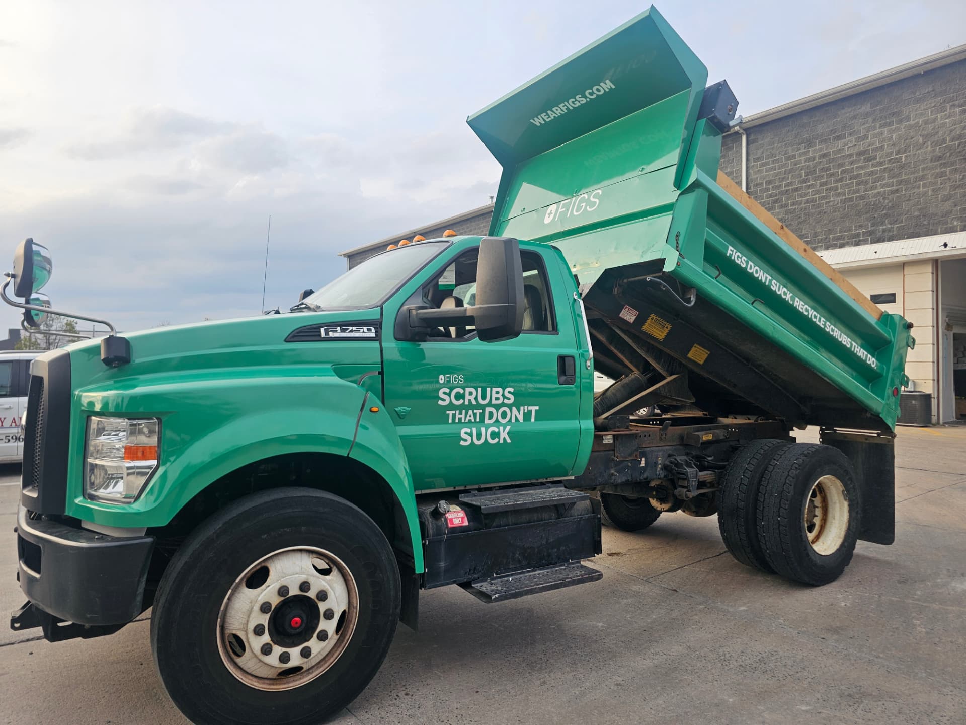 Green FIGS dump truck with printed commercial graphics