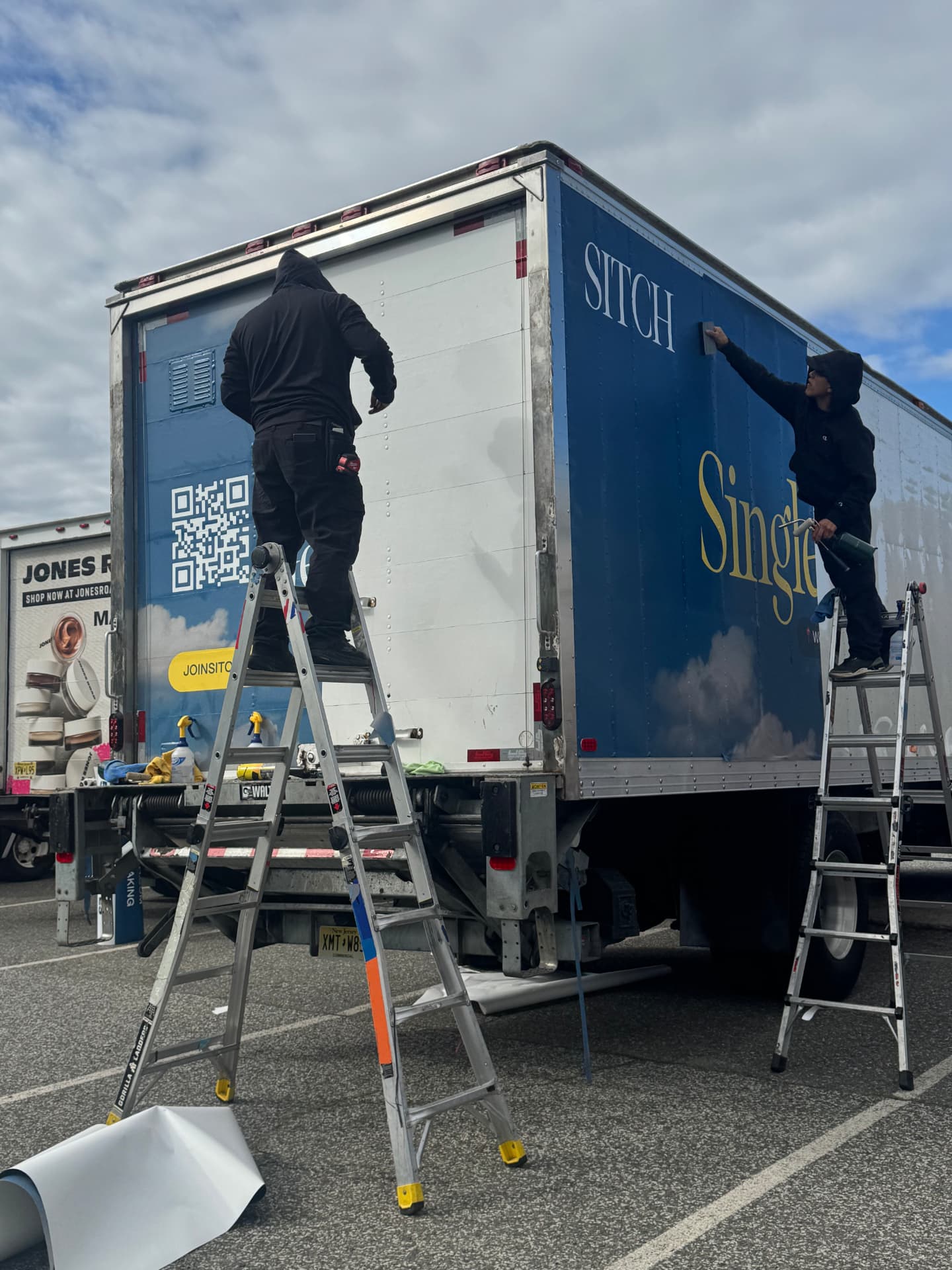 Crew installing a blue Sitch box truck wrap on location